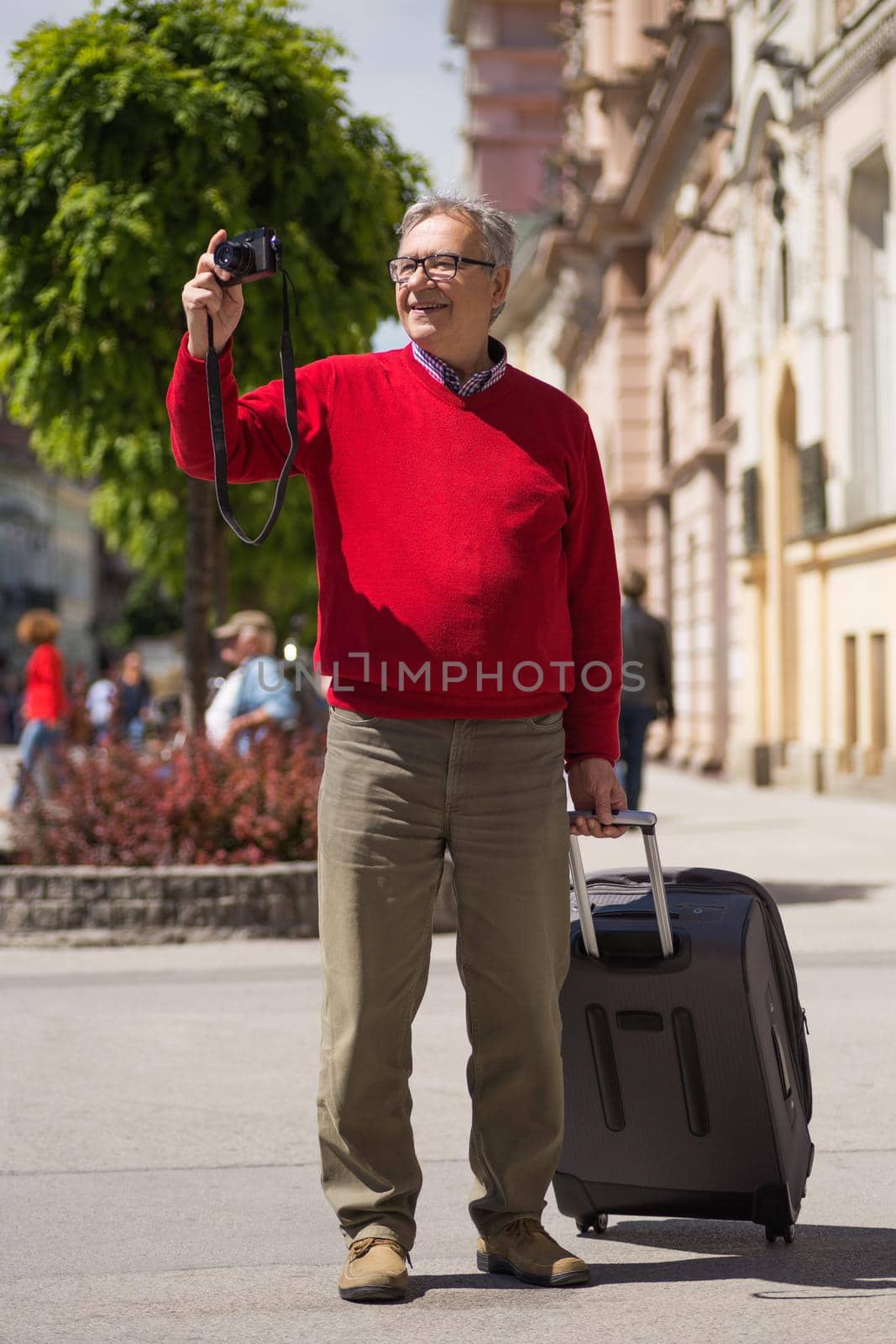 Senior man tourist enjoys photographing at the city.Image is intentionally toned.