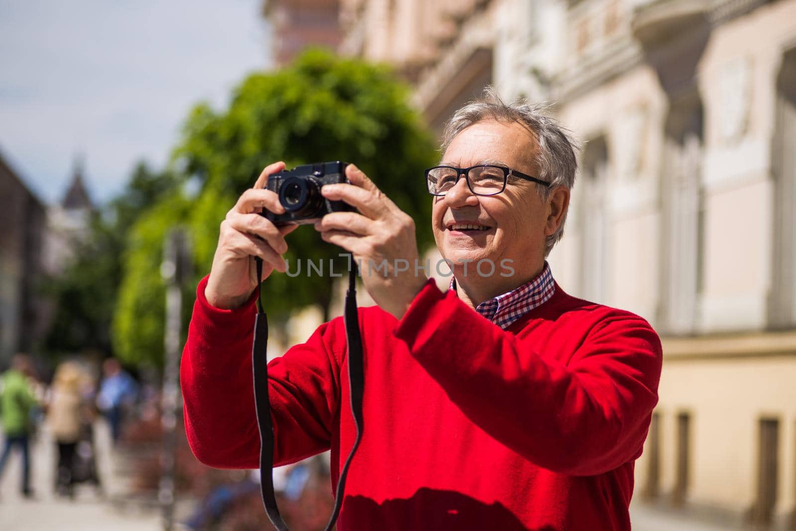 Senior man tourist enjoys photographing at the city.Image is intentionally toned.