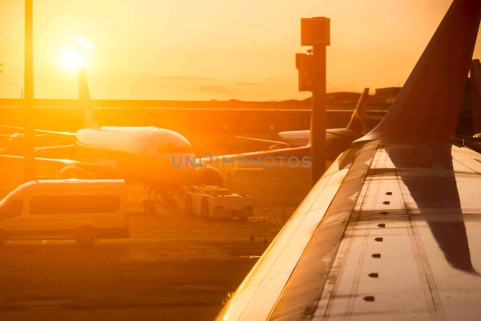 View from the plane window of the wing and other airplanes on the runway at sunset, travel and fly to the journey.