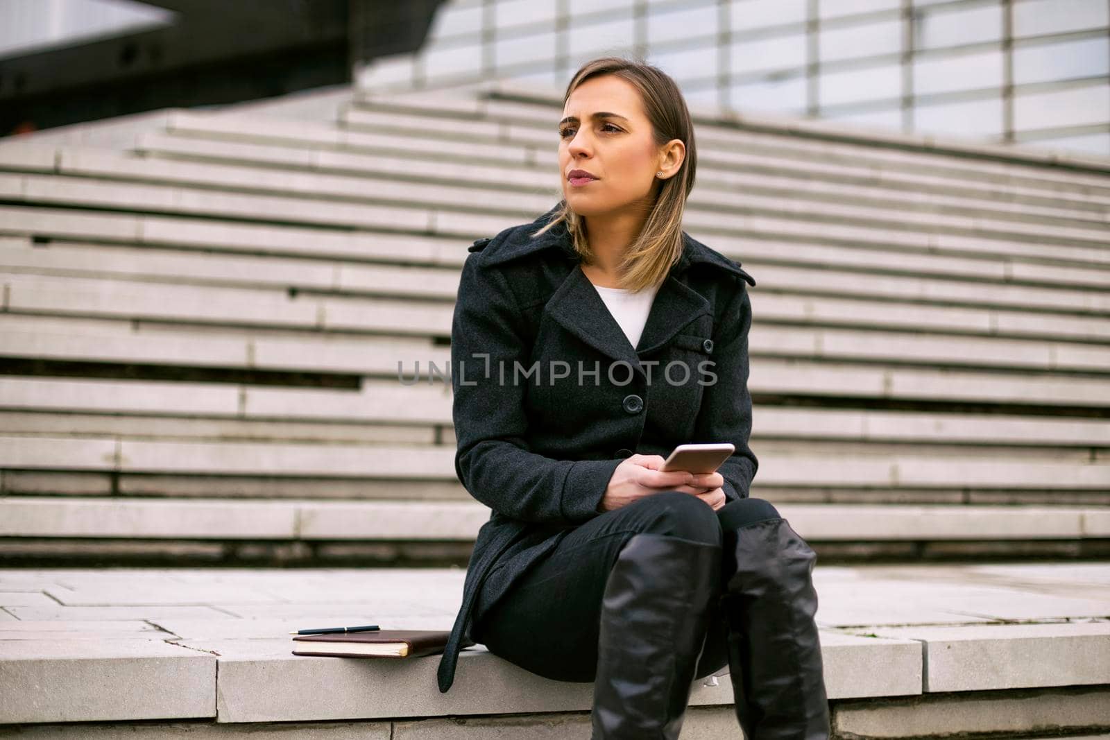 Worried businesswoman using phone while working outdoor.