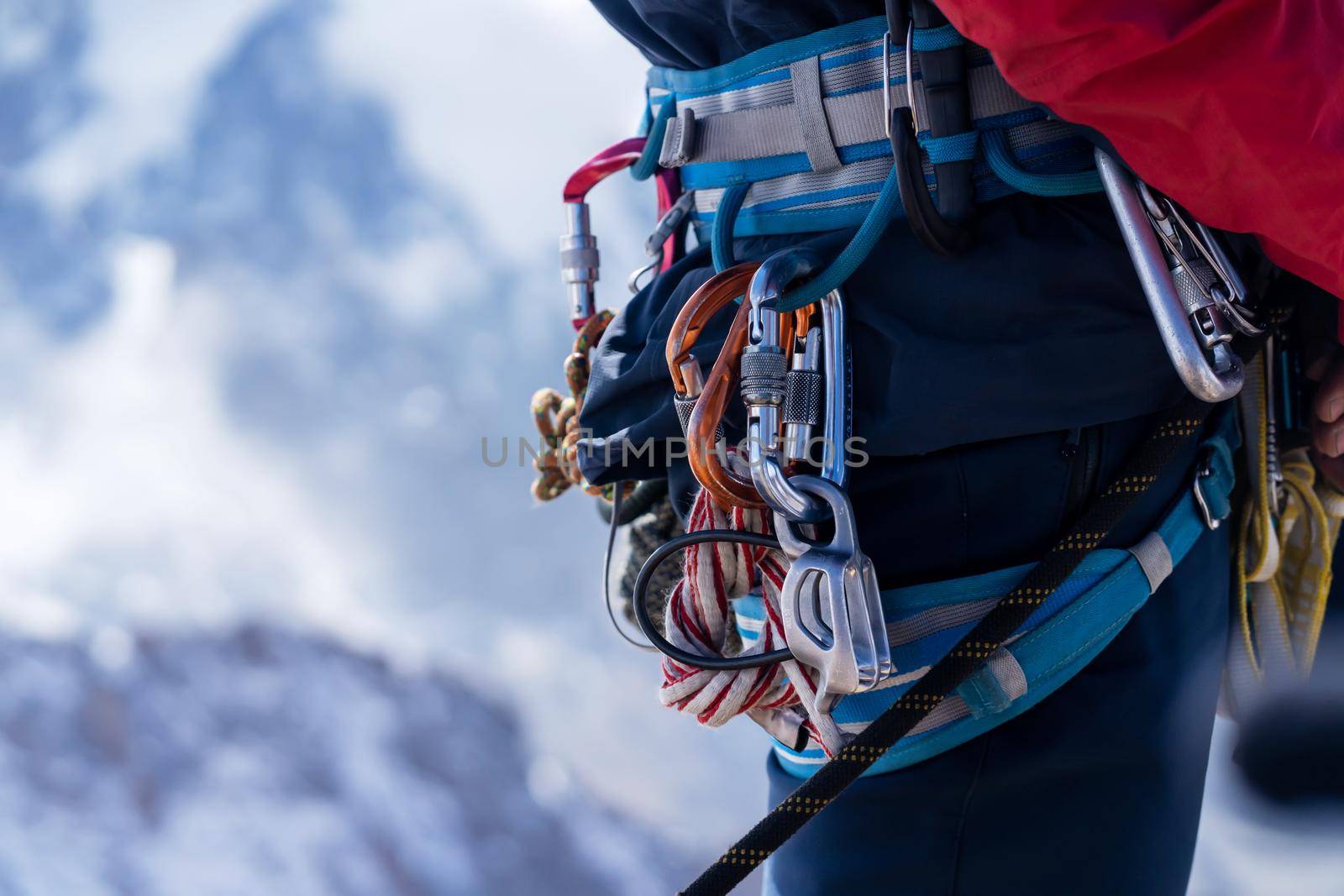 Young man traveler alpinist climbs to the top of a snowy mountain with climbing equipment, harness, carabiners, rope.