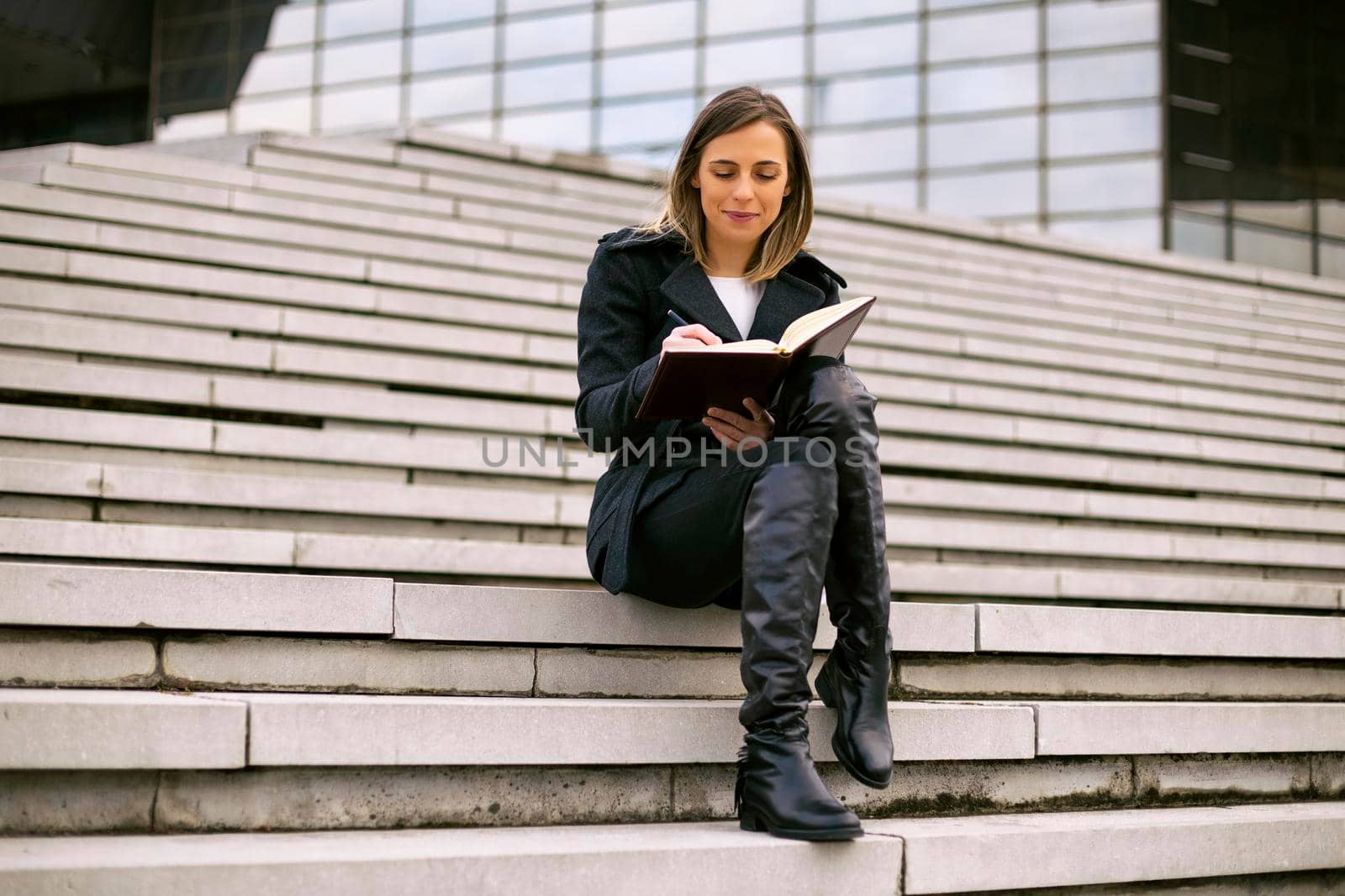 Beautiful businesswoman sitting on the staircase in the city and working.