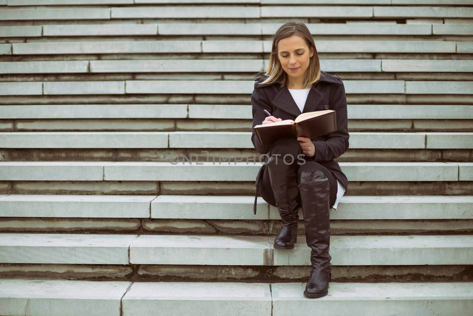 Beautiful businesswoman sitting on the staircase in the city and working.