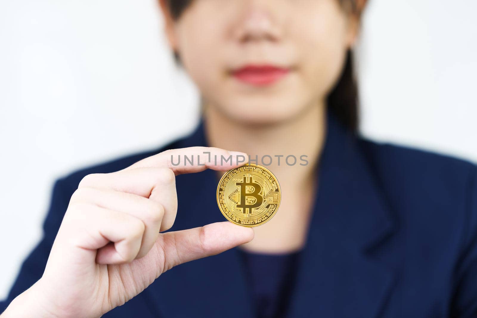 Close up of businesswoman holding some pieces of golden Bitcoin token by stoonn