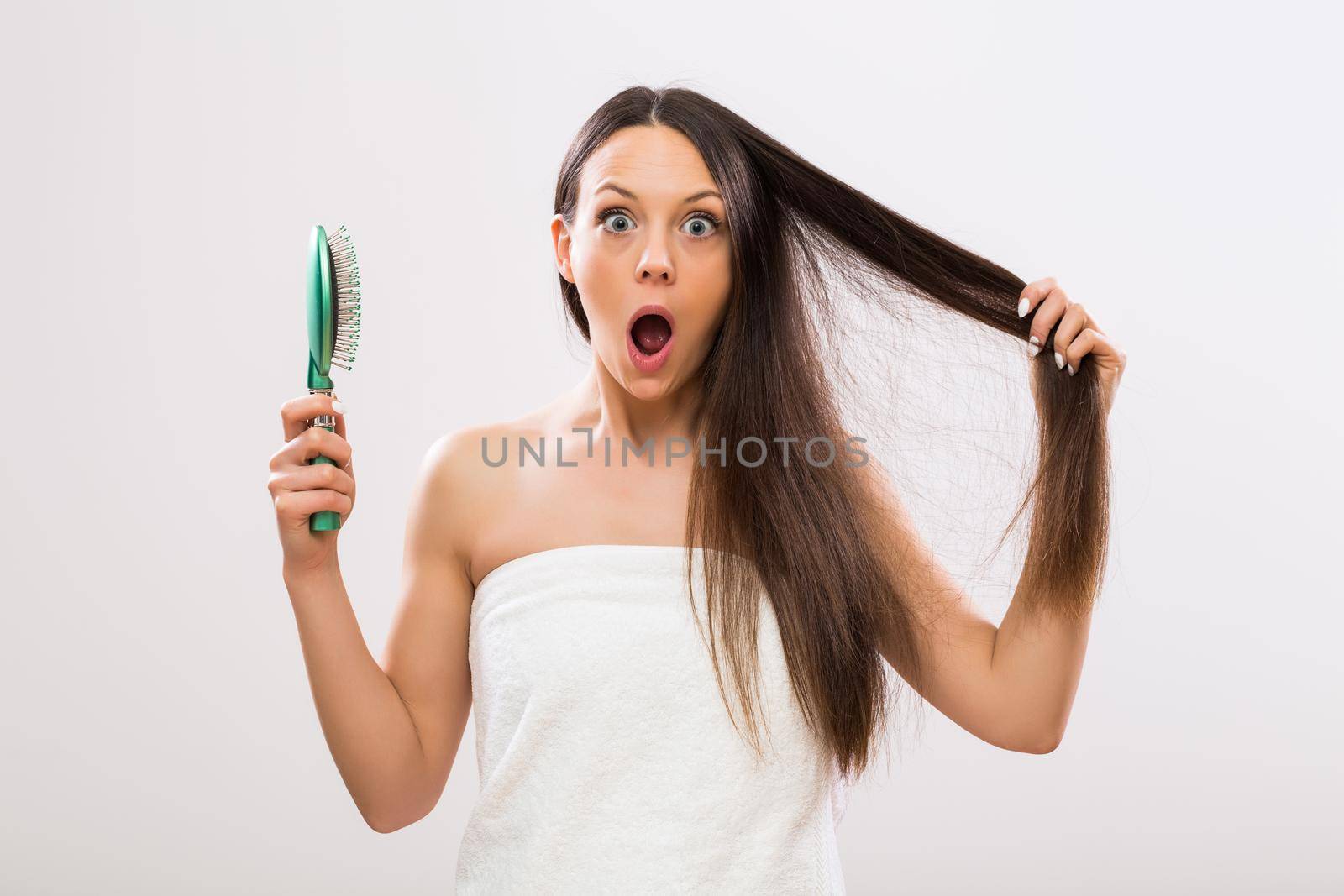 Beautiful woman in panic because of hair loss looking at camera.