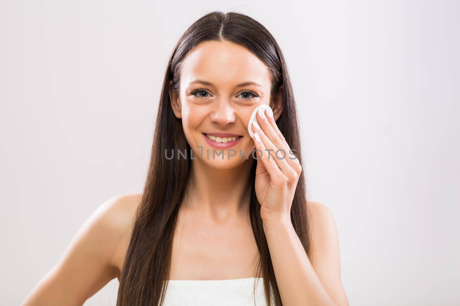 Beautiful brunette woman cleaning her face with cotton pad.