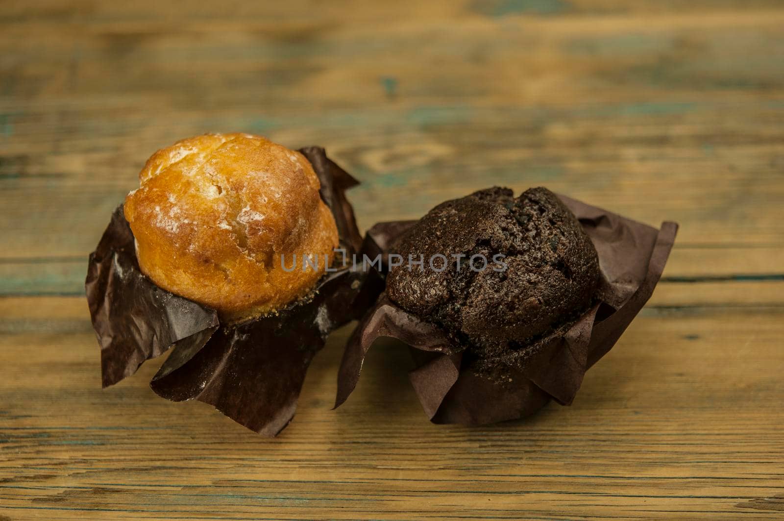 Homemade chocolate and vanilla cupcakes on a wooden table, sprinkled with powdered sugar