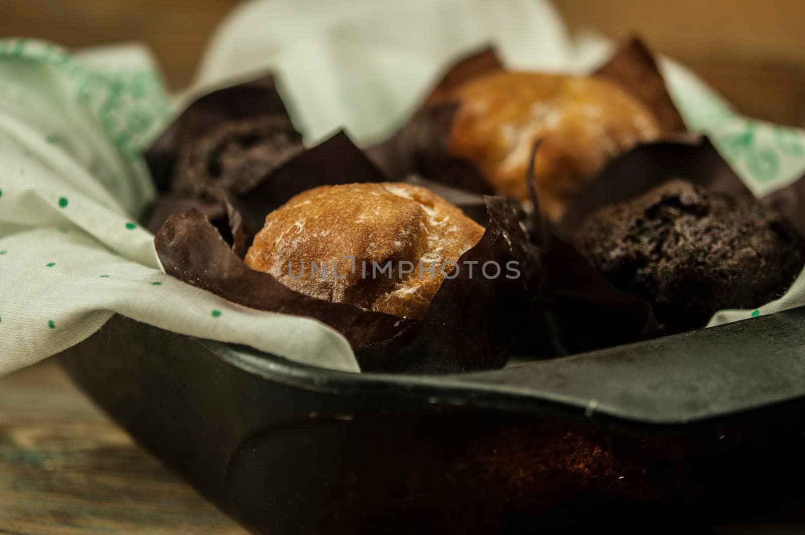 Homemade chocolate and vanilla cupcakes on a wooden table, sprinkled with powdered sugar. Breakfast by inxti