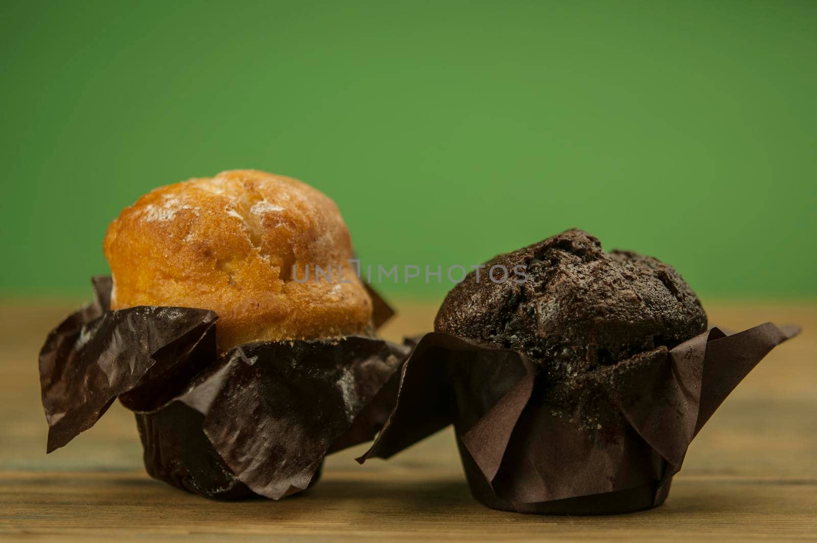 Homemade chocolate and vanilla cupcakes on a wooden table, sprinkled with powdered sugar by inxti