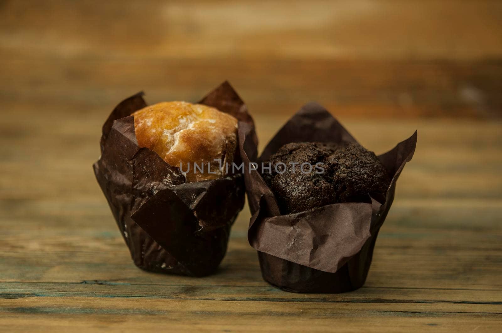 Homemade chocolate and vanilla cupcakes on a wooden table, sprinkled with powdered sugar by inxti