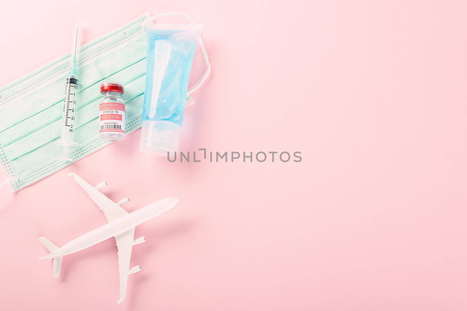 Model plane, COVID-19 coronavirus vaccine vials bottles for vaccination and medical face mask, buy vaccine, tourism worldwide delivery studio shot isolated pink background with copy space for text