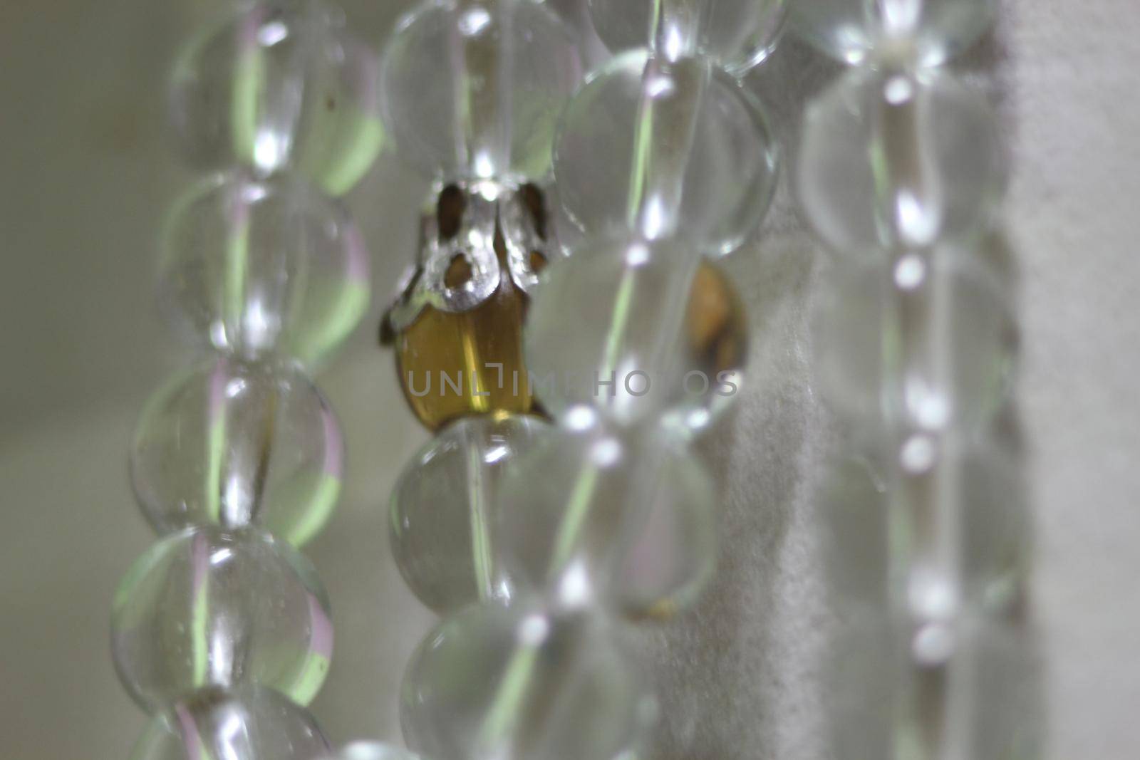 Macro photograph with selective focus of glass shiny prayer beads or rosary with copy space for text. Religion concept of ramadan or Eid for muslims.