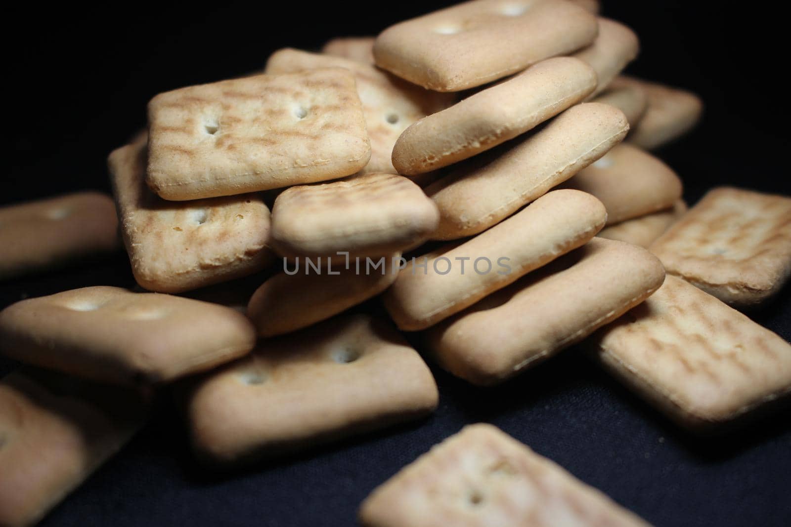 Close up top view of of biscuit cookies. Many rectangular biscuits with small pores on black floor