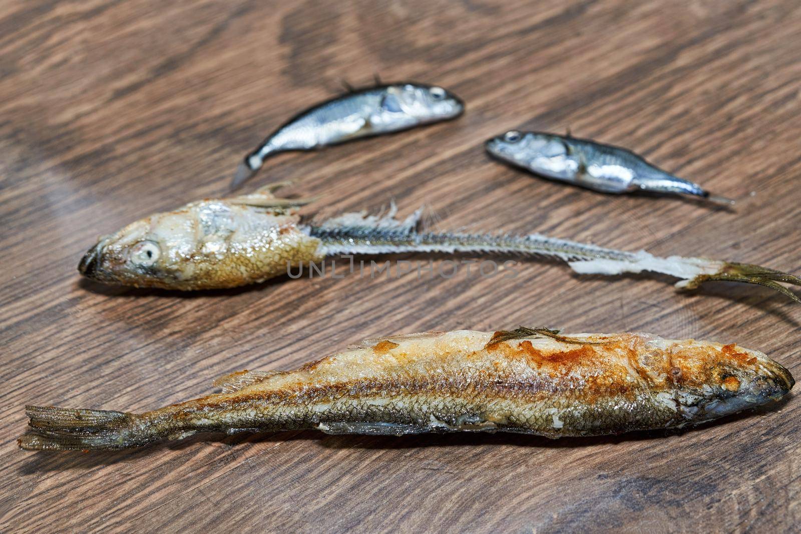 Whole fried fish smelt and fish bones on a plate. Fish before and after eating