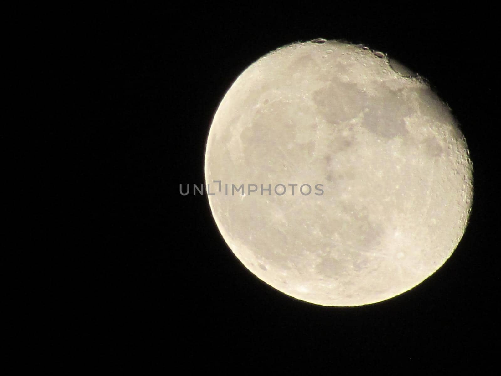 The Moon close-up on a black night sky shot through a telephoto camera. by Photochowk