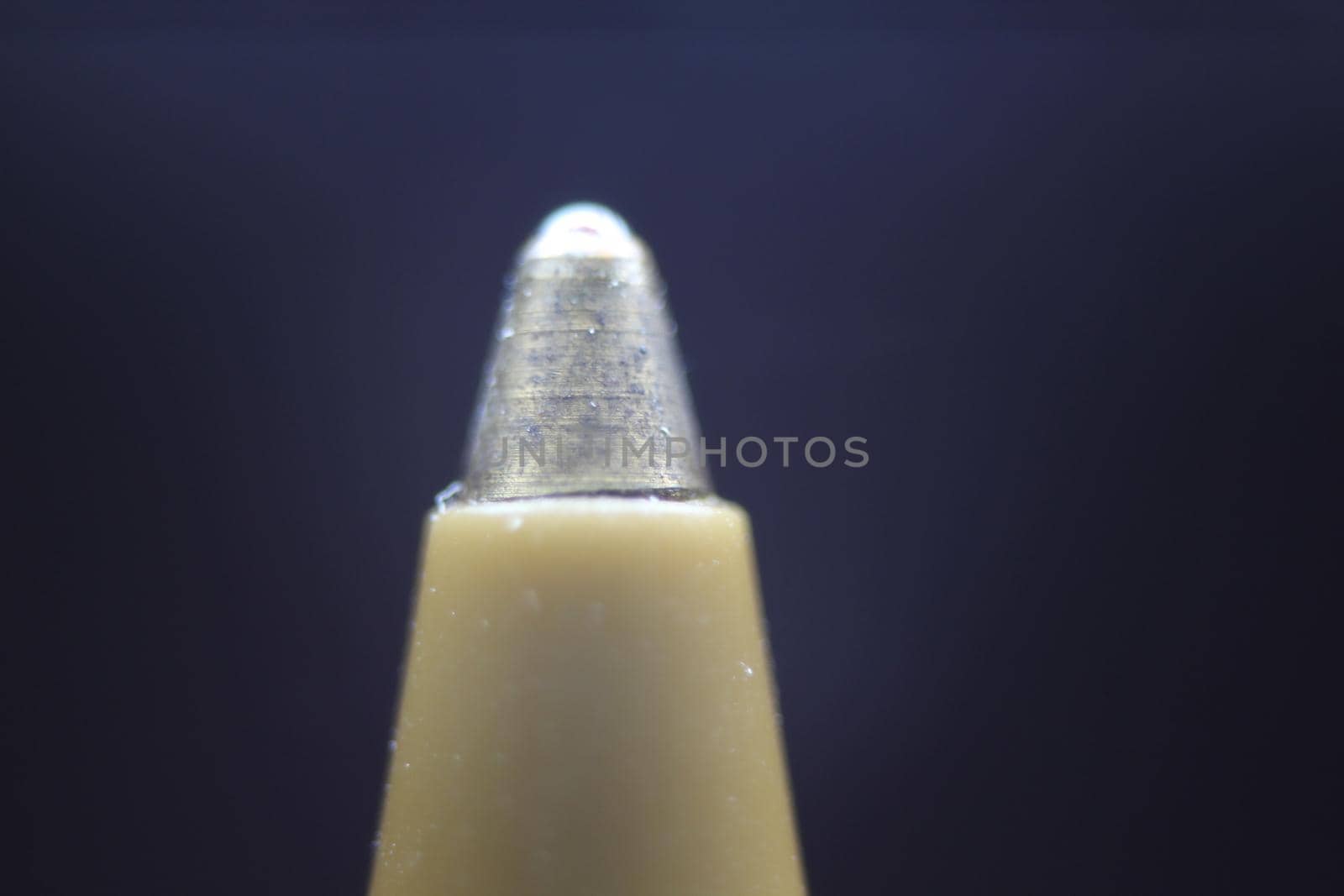 Macro photo of ballpoint pen tip with dark grey background. Extreme macro image of metal ballpoint pen on grey background.