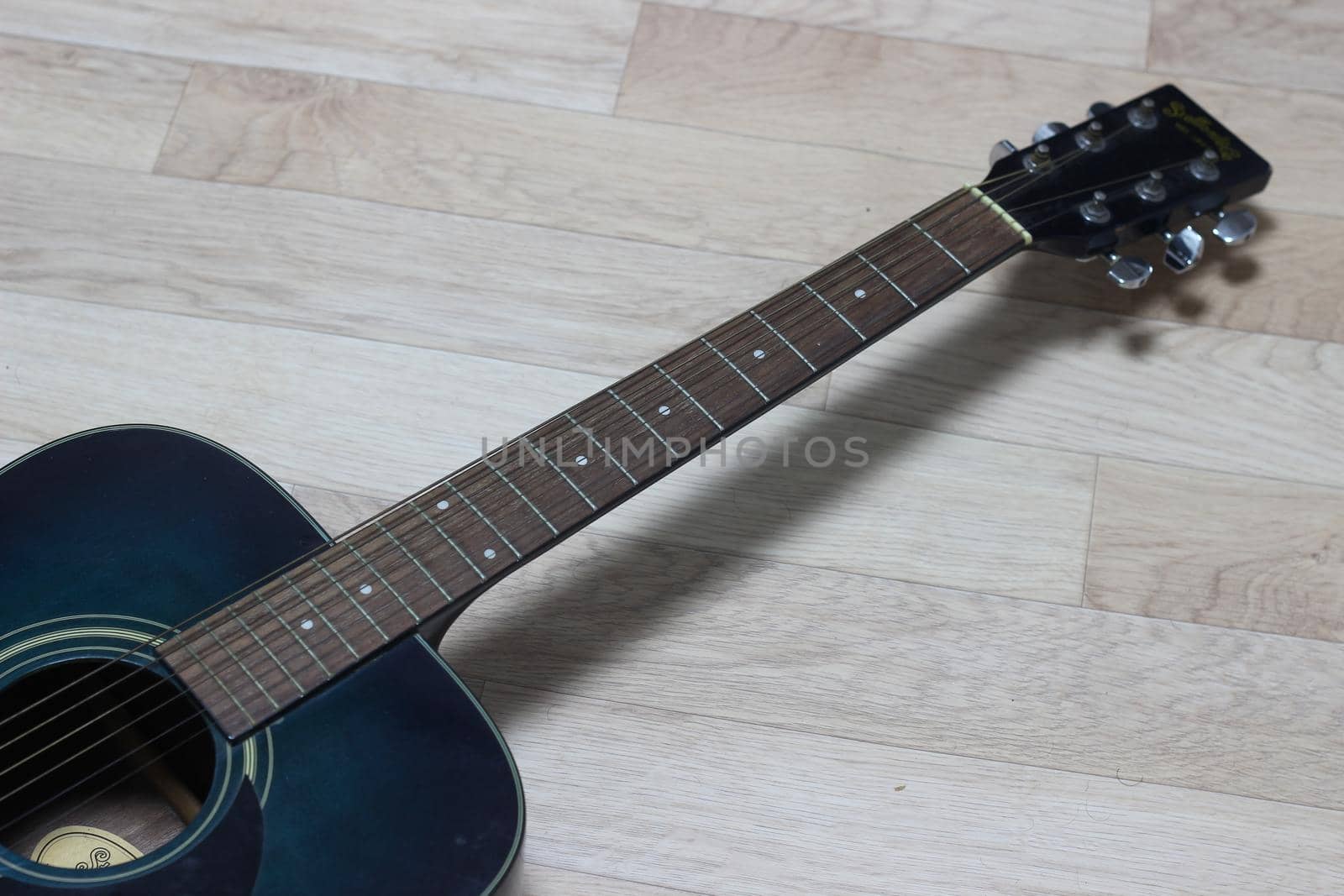 Close up of music guitar. Acoustic guitar with strings on a wooden floor