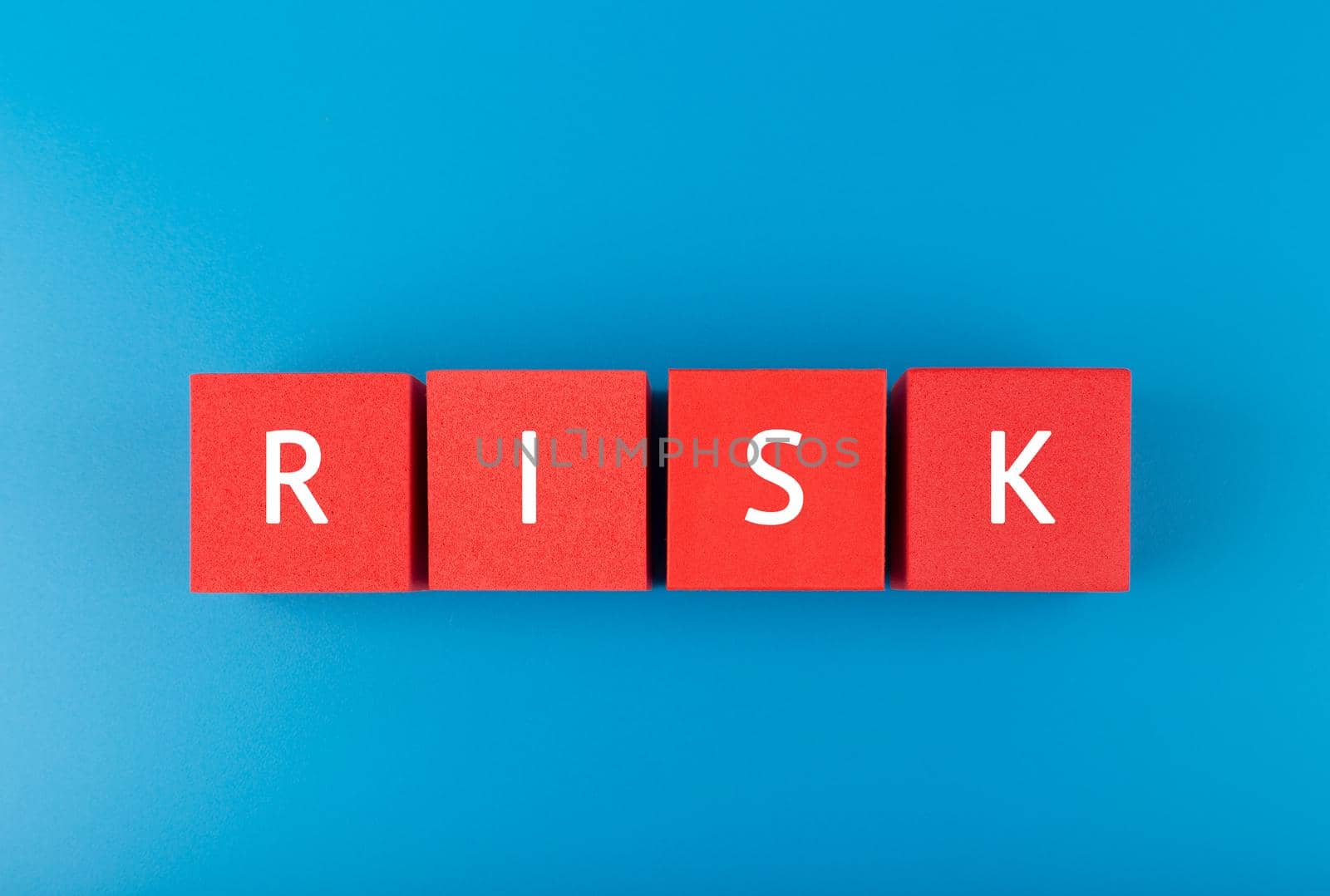 Risk single word written on red cubes against blue background. Concept of risk and danger in business, social life, decisions or strategy