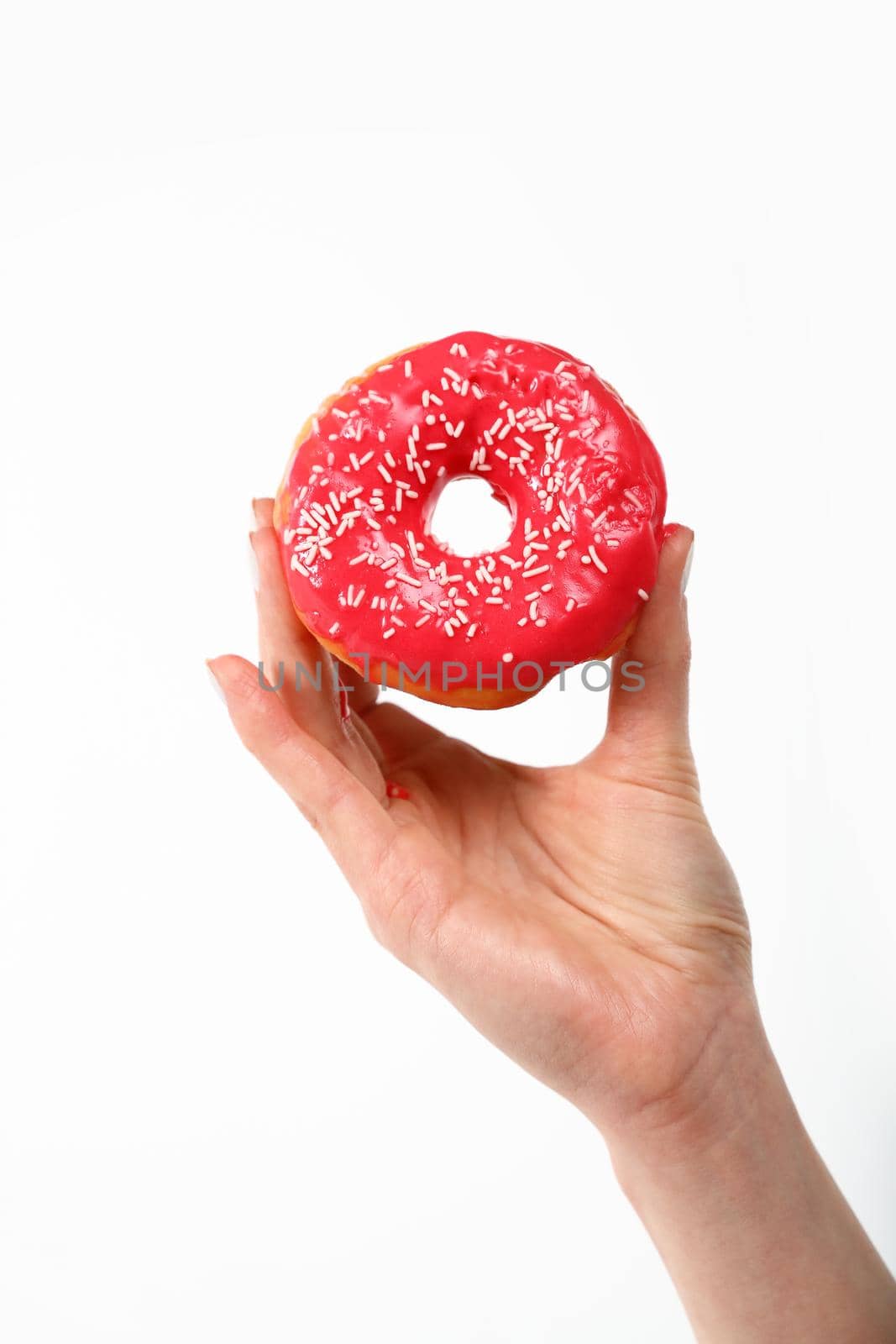 Close up Caucasian woman hand holding one red icing glazed ring doughnut isolated on white background, symbol of unhealthy eating concept, low angle, side view