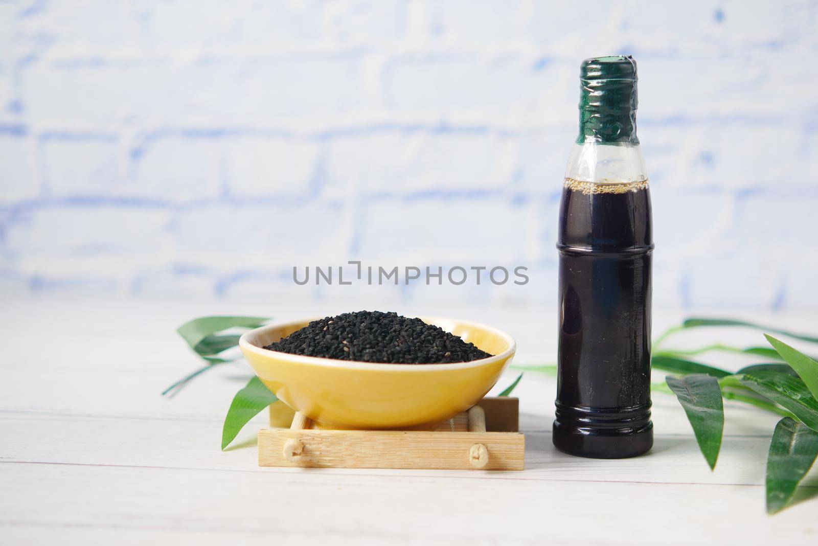 Black Cumin in a bowl with oil in a jar on table