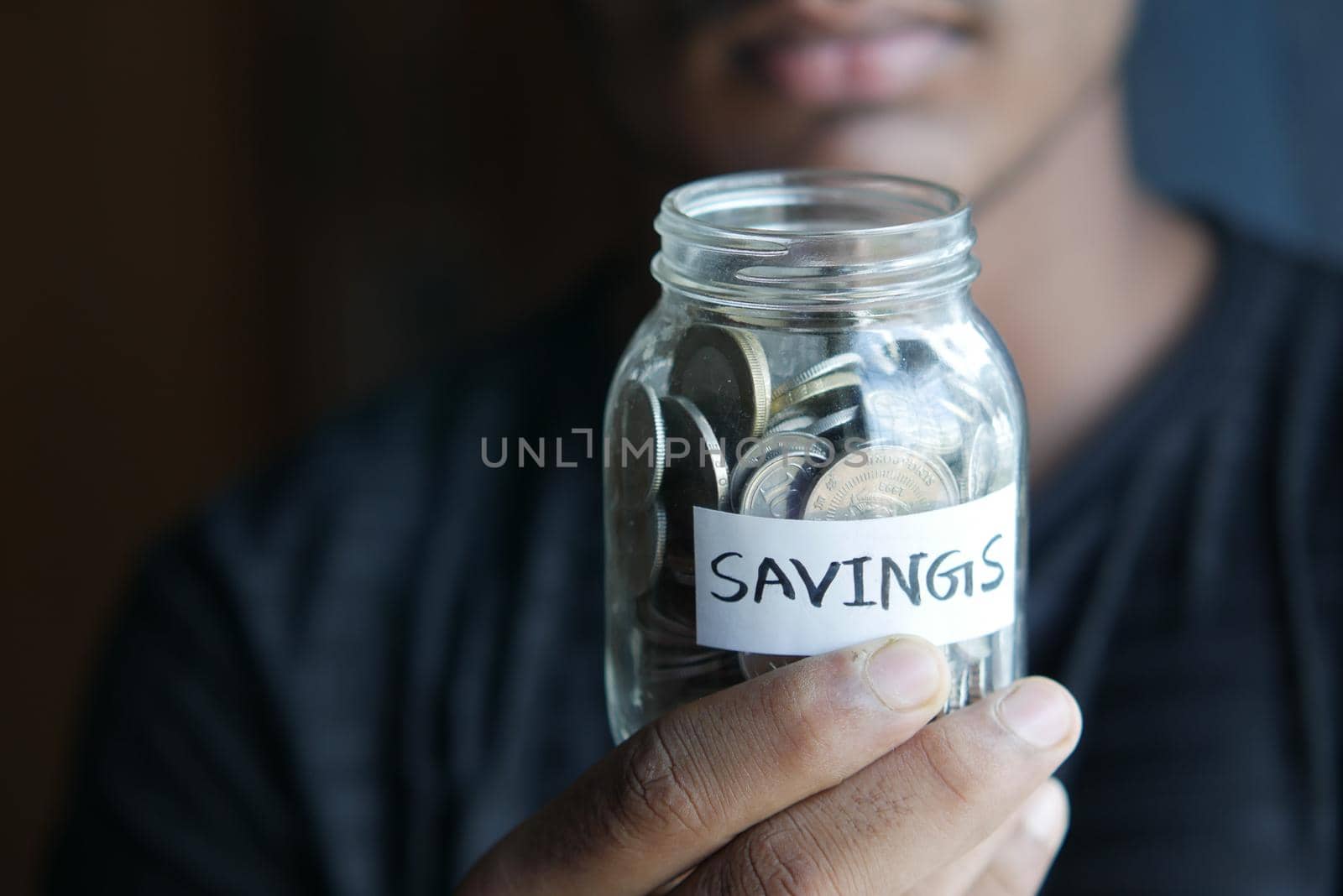 young man hand hold saving coins jar .
