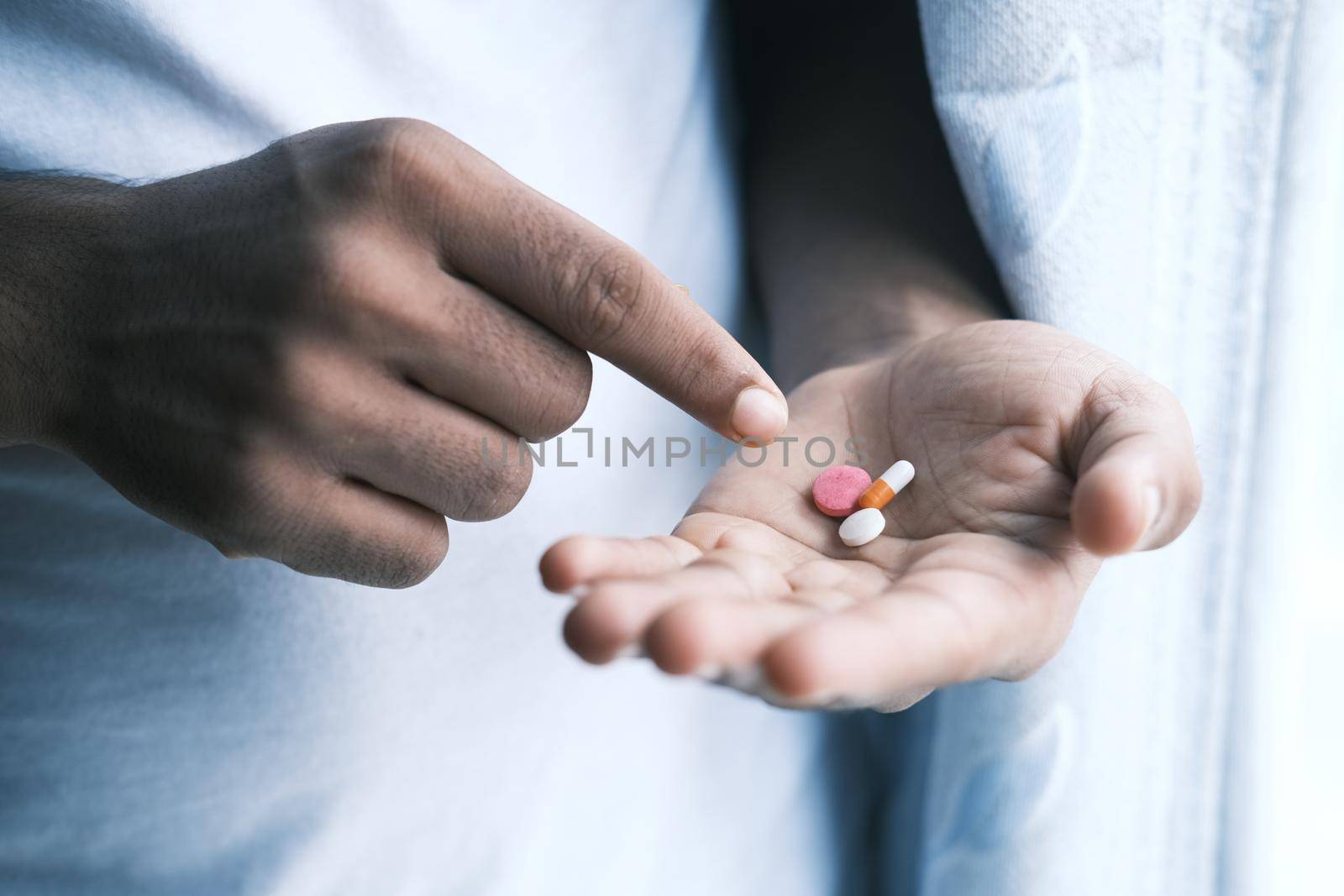 man's hand with pills spilled out of the container .