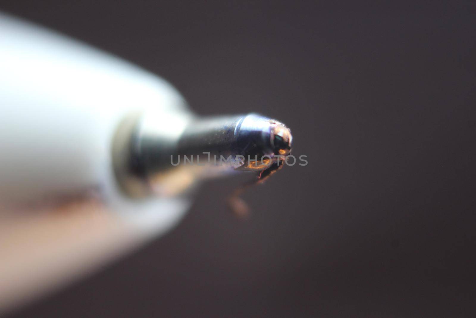 Macro photo of ballpoint pen tip with dark grey background. Extreme macro image of metal ballpoint pen on grey background.