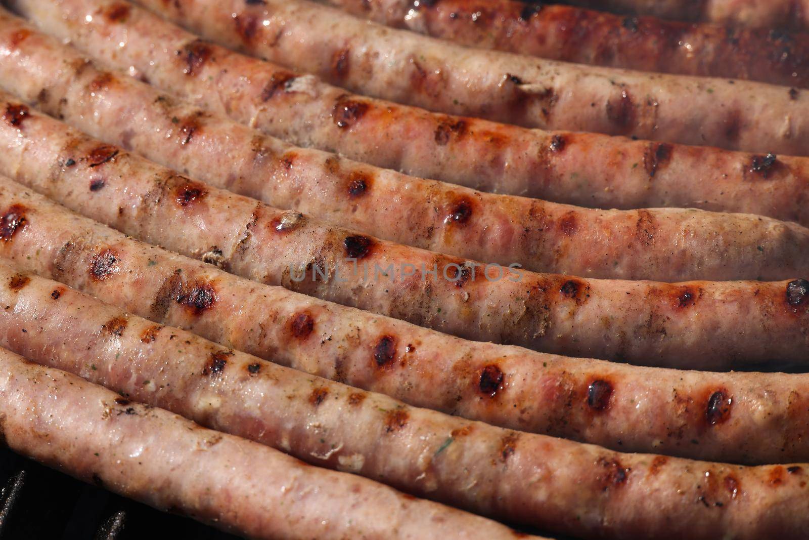 Close up cooking meat sausages on grill, smoking and broiling them, high angle view