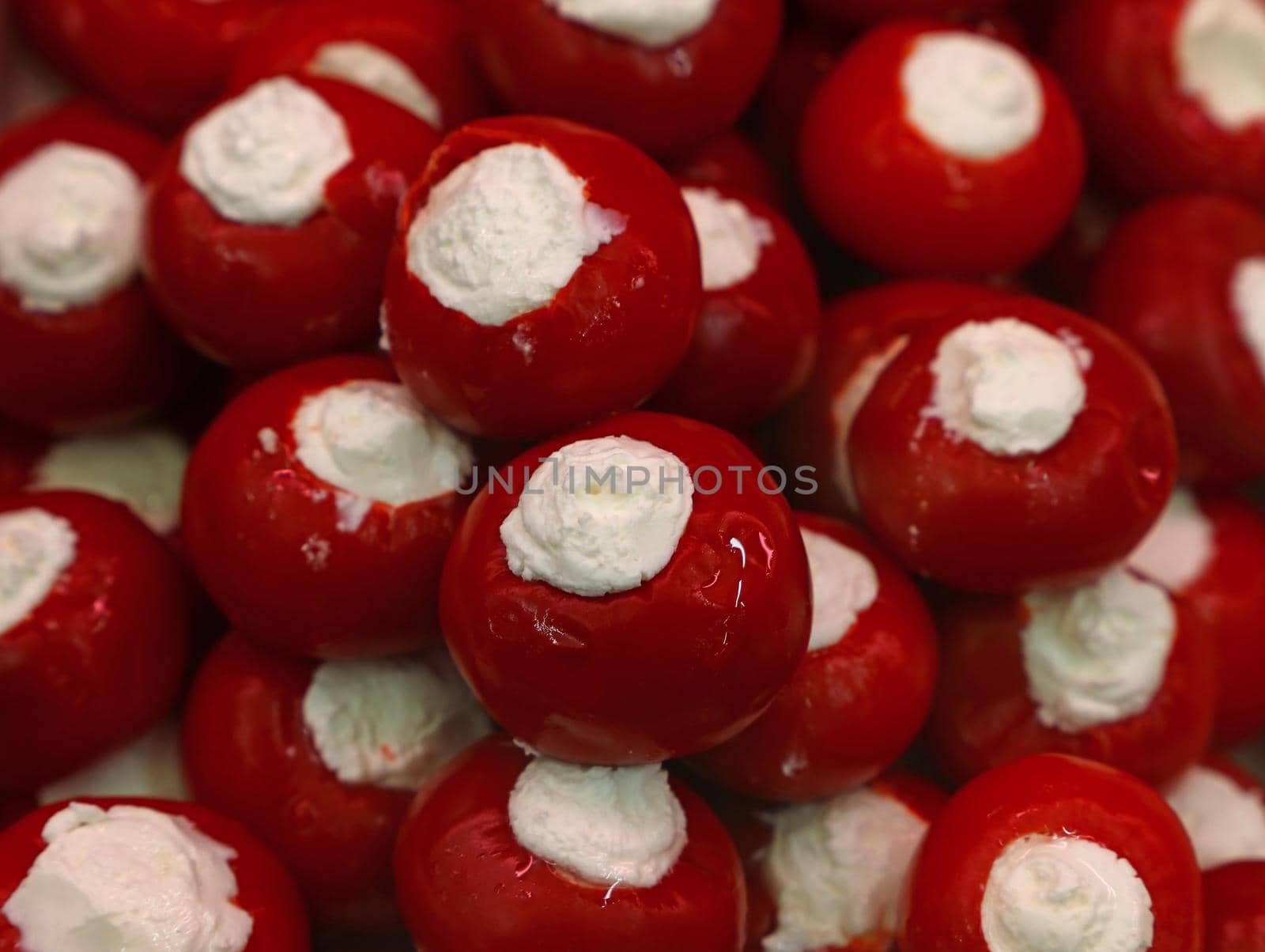 Close up pickled red hot Italian pepperoncini round pepper stuffed with fresh white cheese on retail display, high angle view