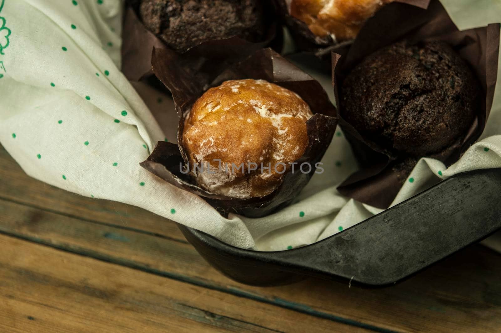 Homemade chocolate and vanilla cupcakes on a wooden table, sprinkled with powdered sugar. Breakfast by inxti