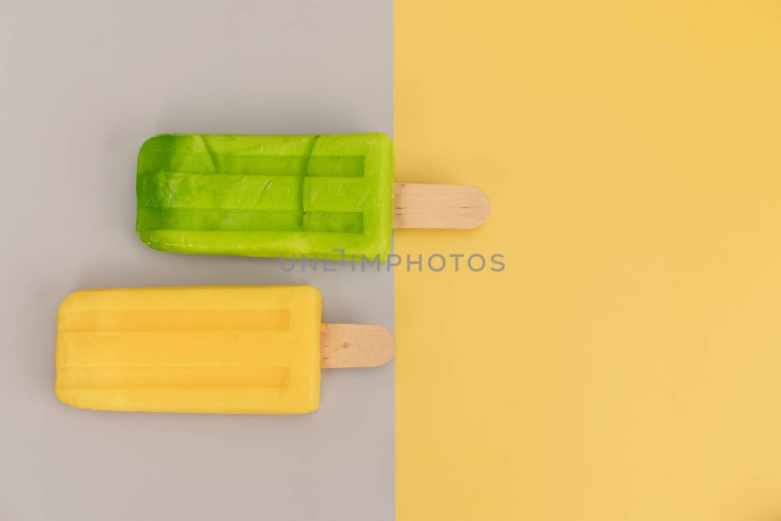 Ice cream stick on gray and yellow background. by Buttus_casso