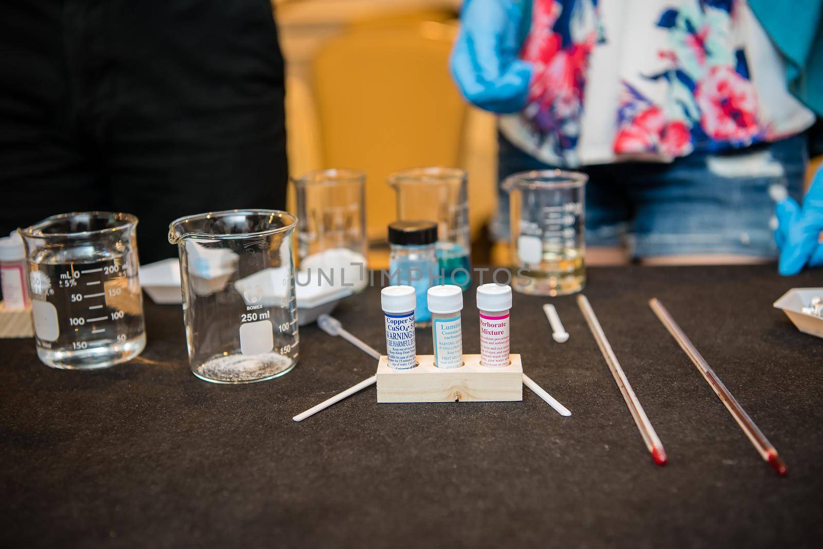 A close up product photo of science experiment materials including colorful liquid filled beakers and various vials and stirring mechanisms.