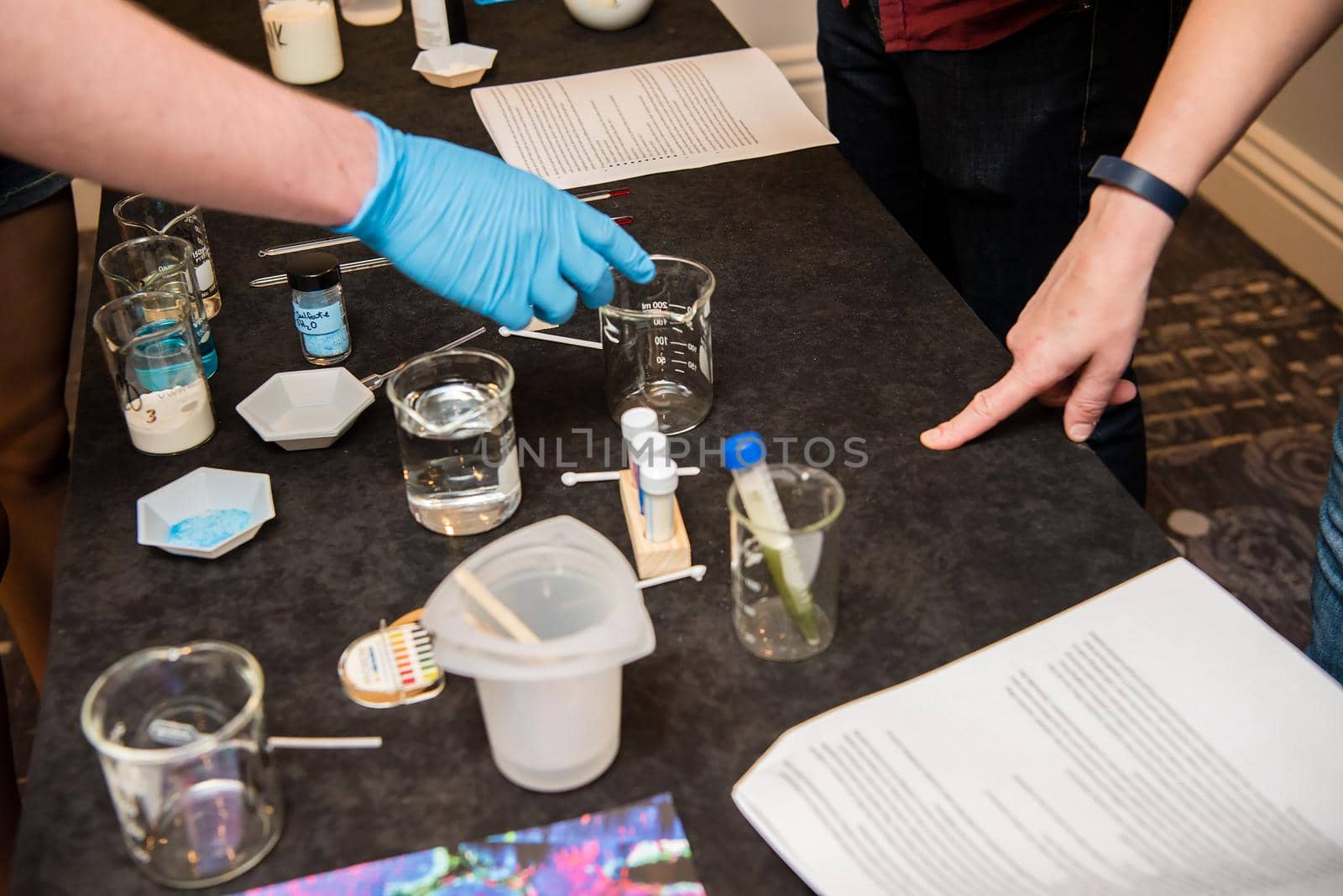 A close up product photo of science experiment materials including colorful liquid filled beakers and various vials and stirring mechanisms.