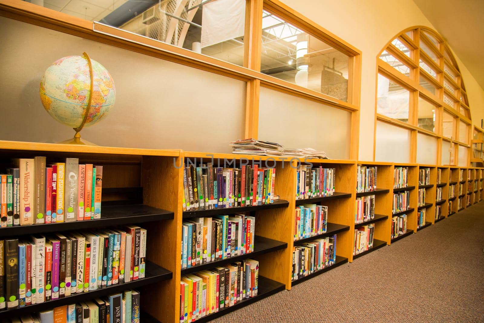 Colorful books in a school library with a globe sitting on the top shelf. Learning setting