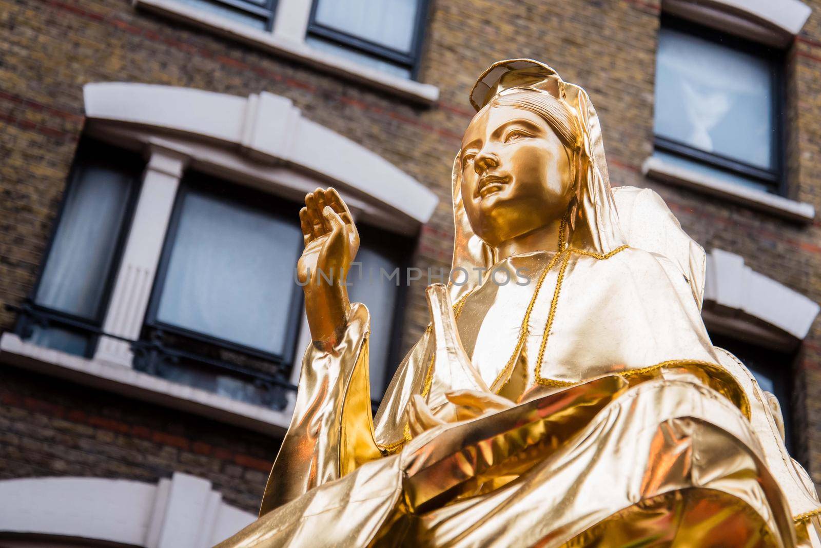 London, UK - January 29, 2017: Chinese New Year celebration parade with gold woman statue holding right hand up