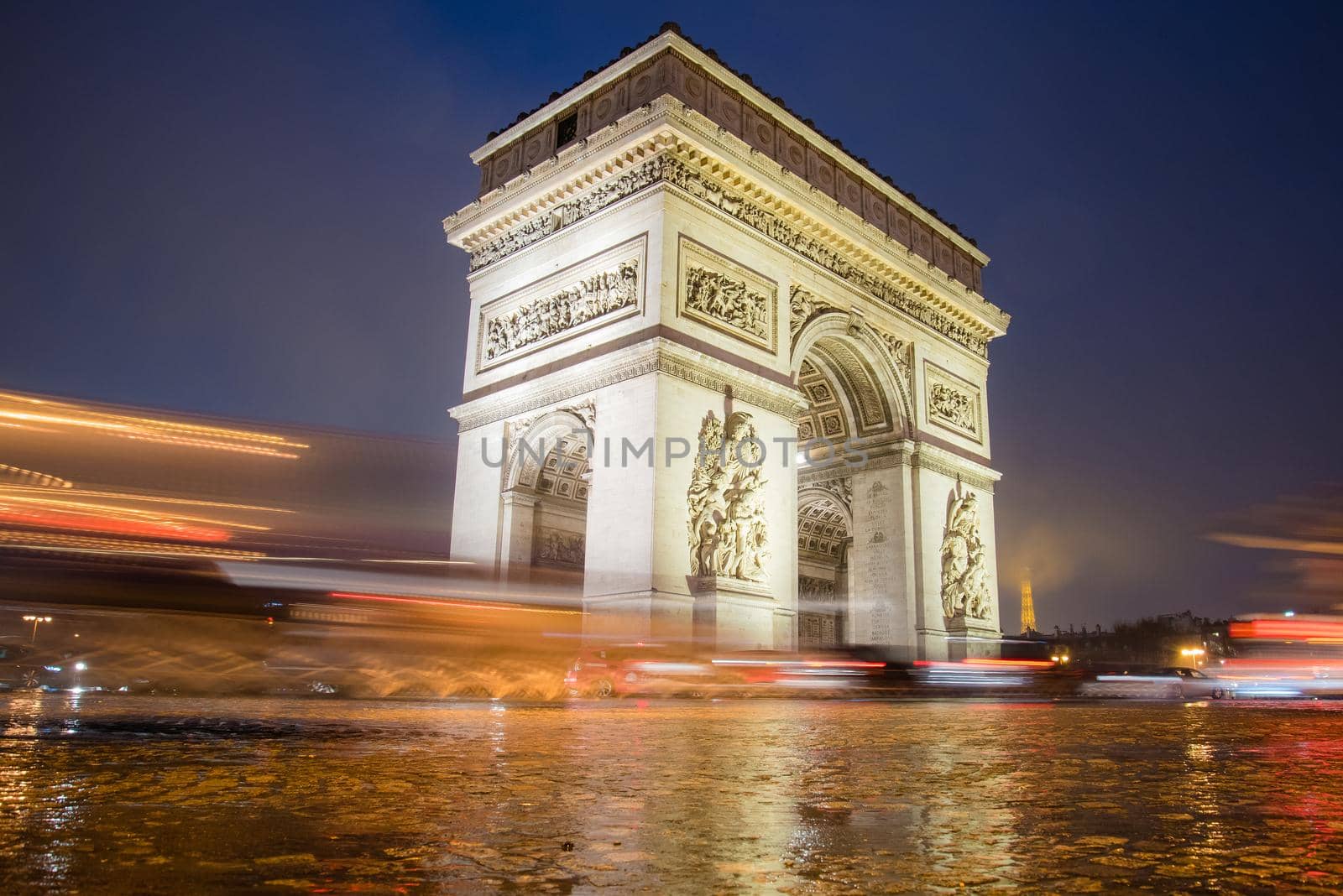 Paris, France - February 3, 2017: Paris Arc de Triomphe long exposure artistic image with traffic lights on a rainy night. Majestic Structure