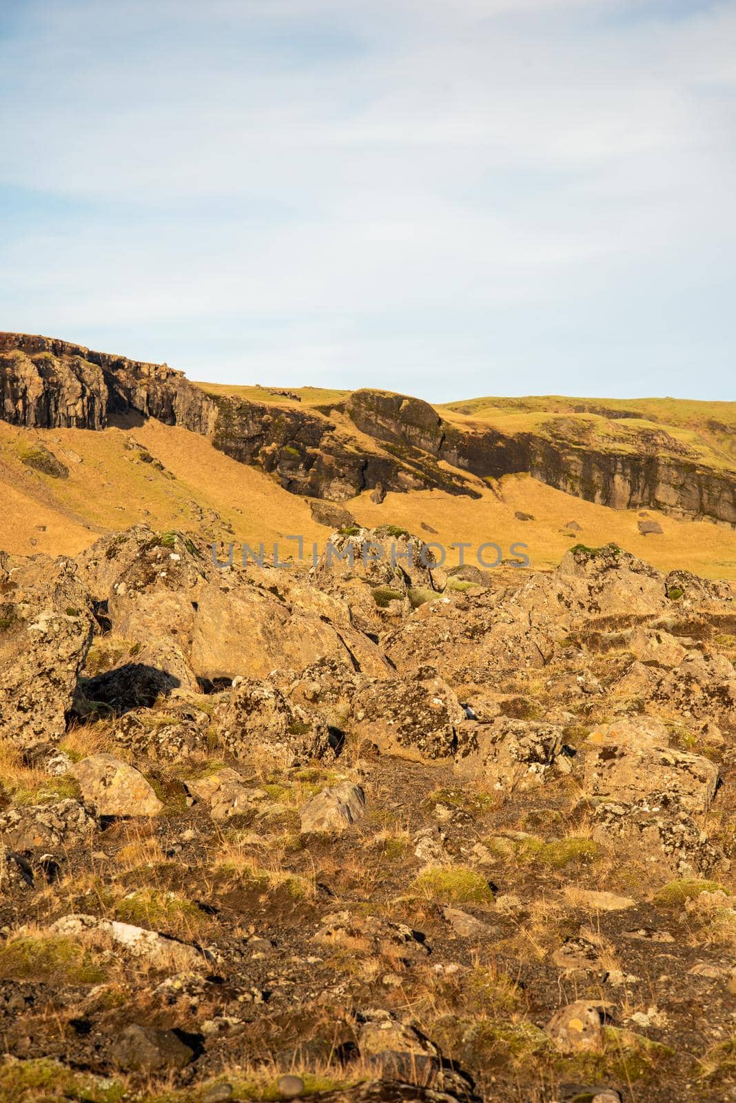 Icelandic topography with warm brown and orange tones and rocky texture with a blue sky by jyurinko