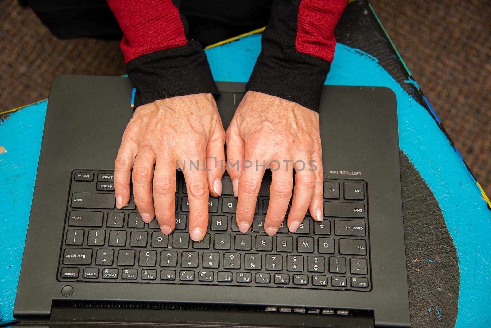 View of woman's hands typing on a black keyboard laptop. by jyurinko