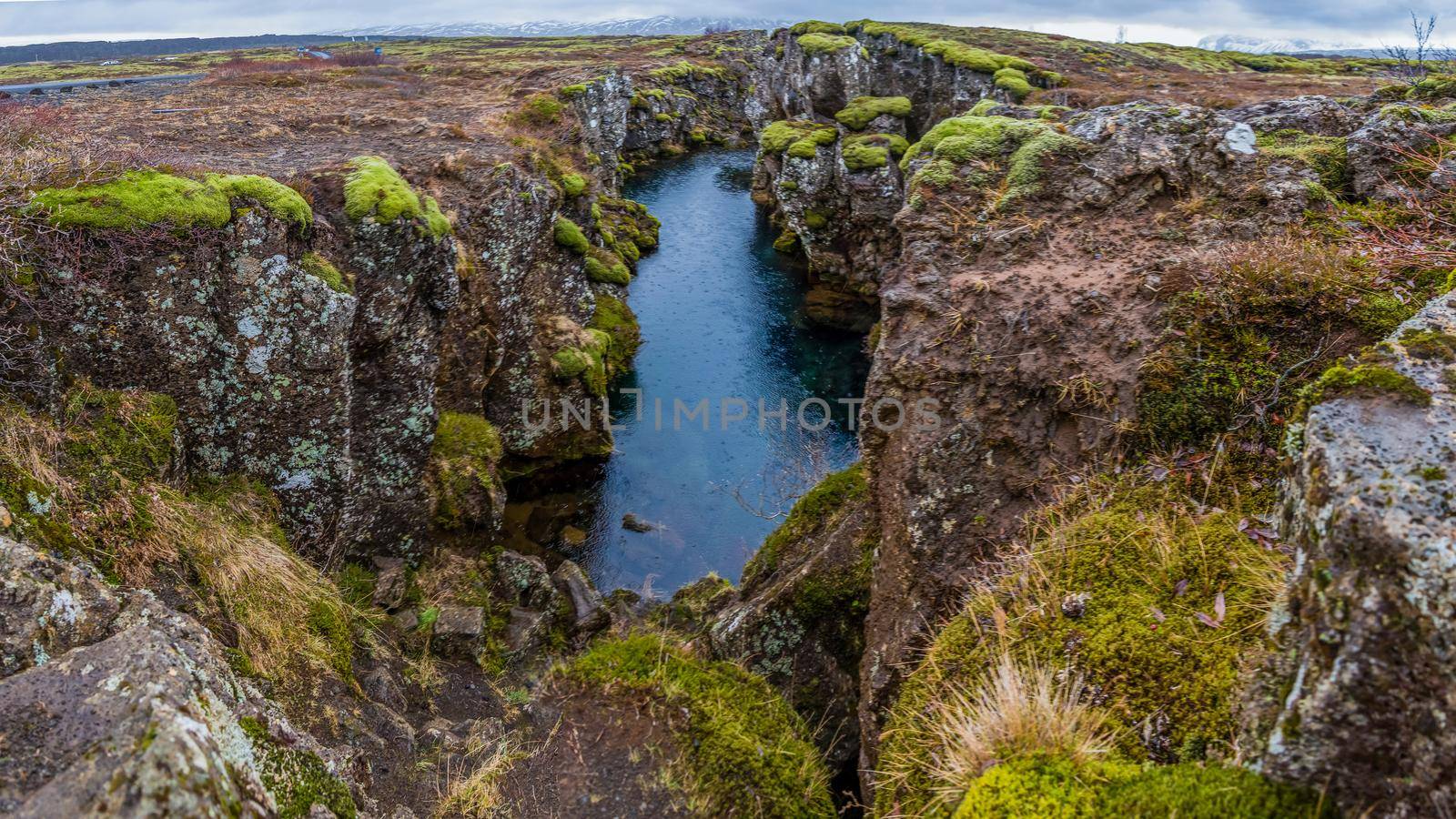 Mossy Icelandic canyon with straight riverbed rainy by jyurinko