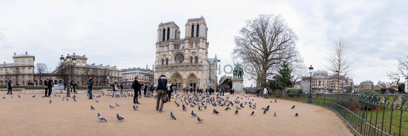 Paris, France - February 3, 2017: Wide angle view of doves and unidentified tourists in front of the Notre Dame de Paris. It is among the largest and most well-known church buildings in the world.