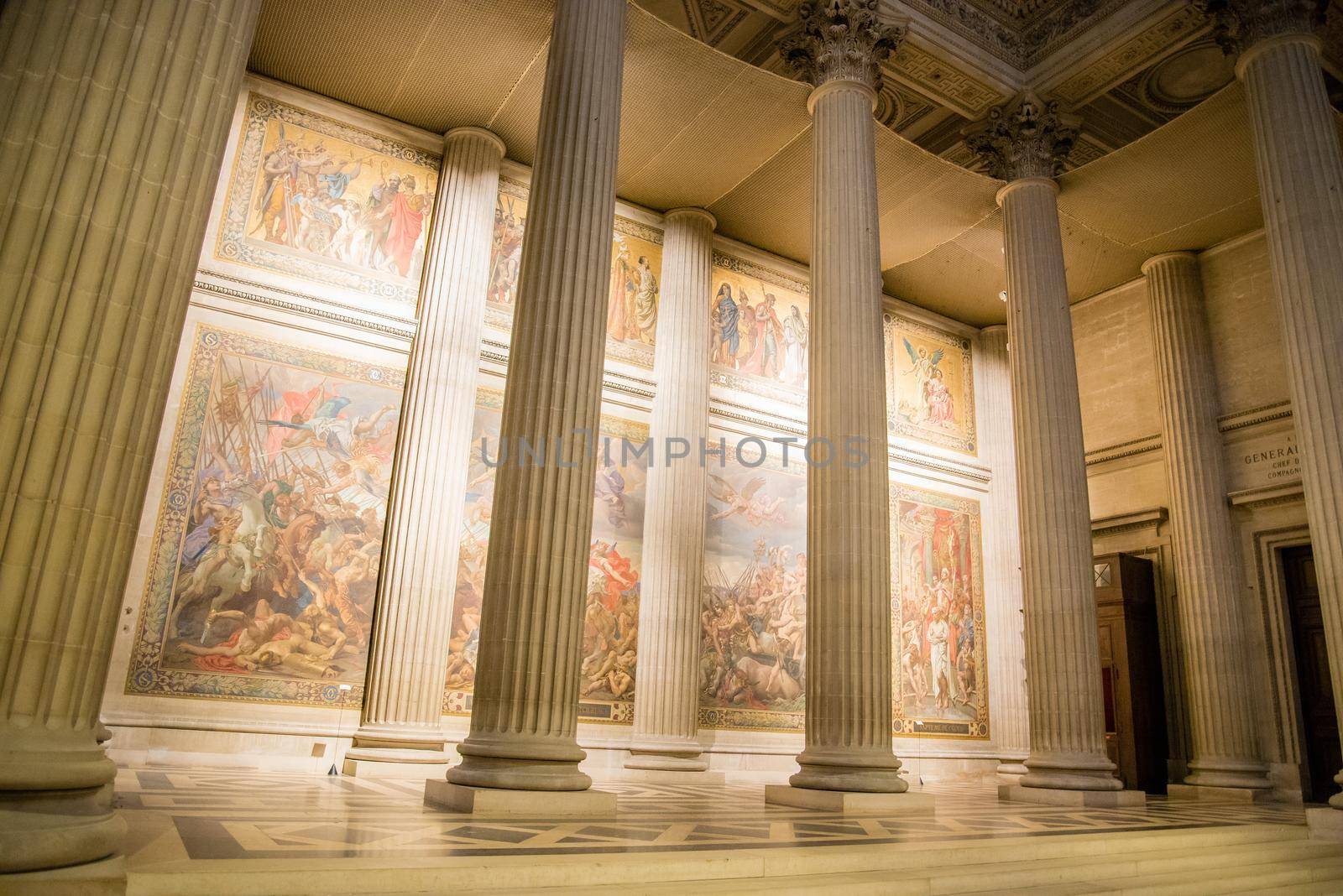 Paris, France - February 3, 2017: Interior photo of tall pillars with colorful glowing art murals in the background in a Paris art museum.