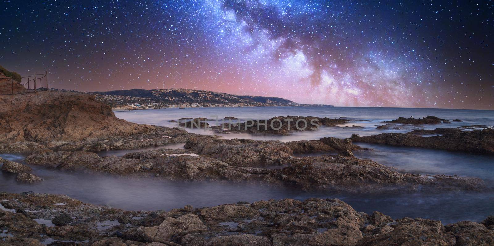 Milky way shimmers over the ocean water as it cascades over rocks by steffstarr