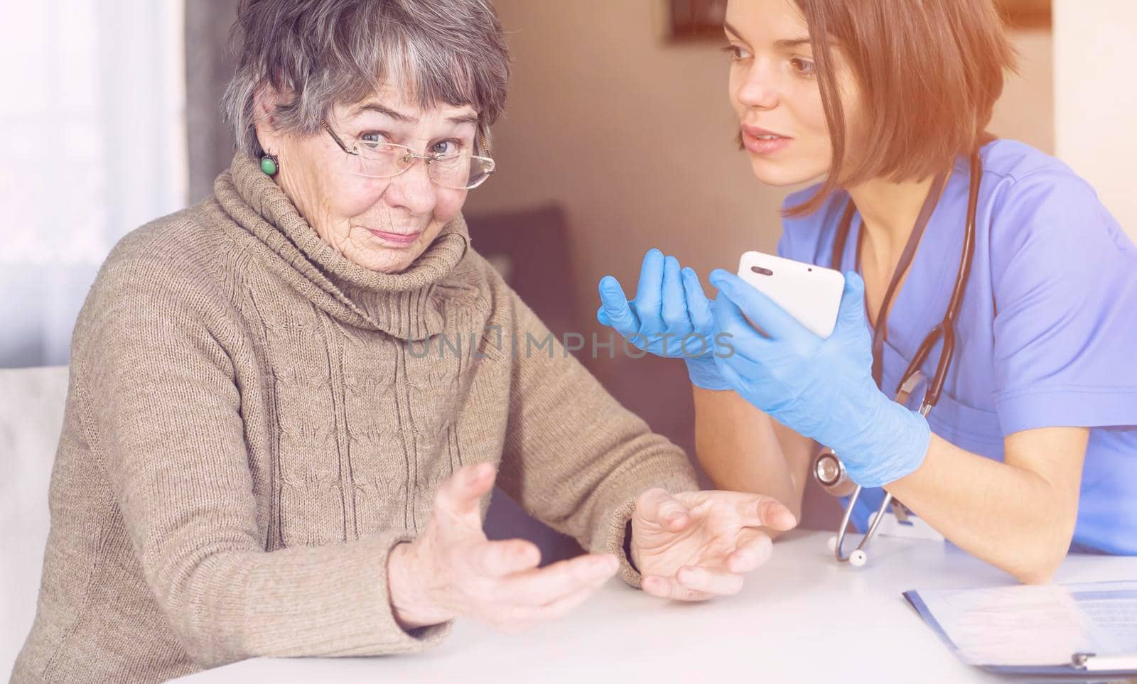 A nurse in a medical suit takes care and explains to an elderly patient by africapink