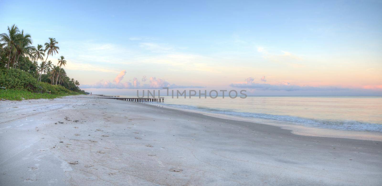 Sunrise over old pier on the ocean at Port Royal Beach in Naples, Florida.