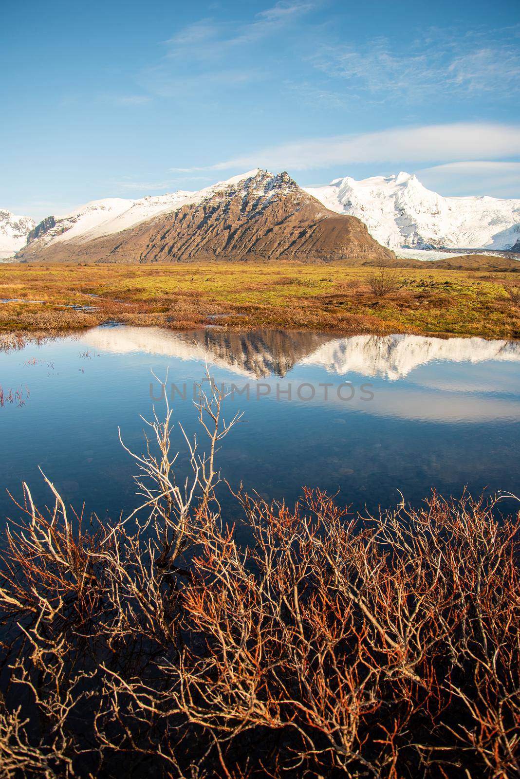 Icelandic mountain range with beautiful snowcapped mountains reflected into still water.