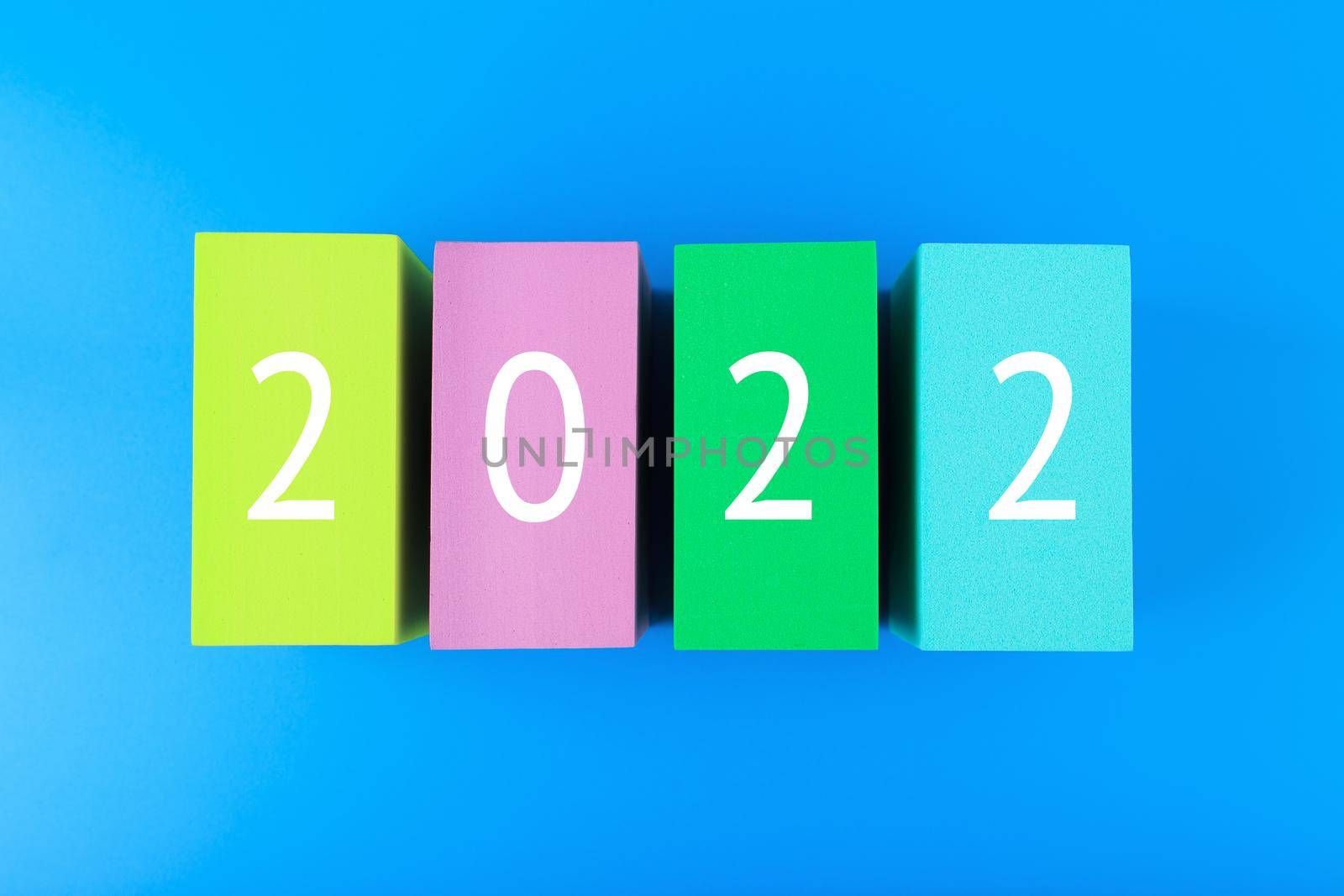 New Year 2022 blue minimal concept. Modern flat lay composition with colorful toy blocks with written 2022 numbers on vibrant blue background