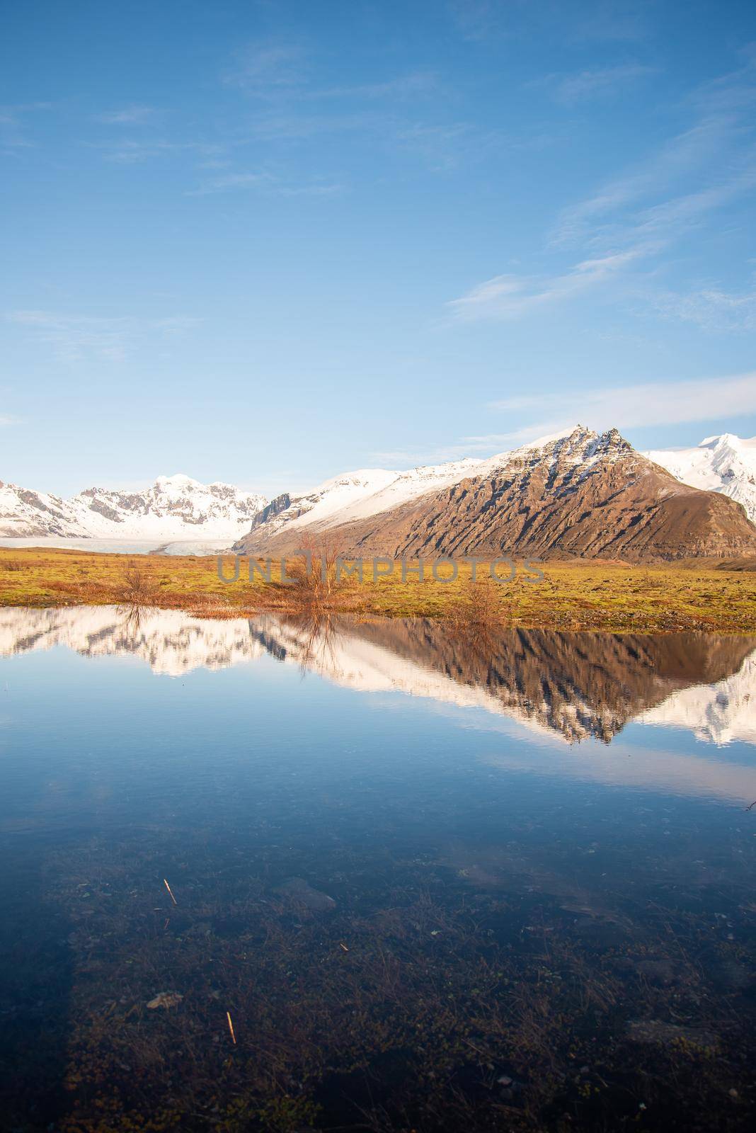 Icelandic mountain range with beautiful snowcapped mountains reflected into still water.