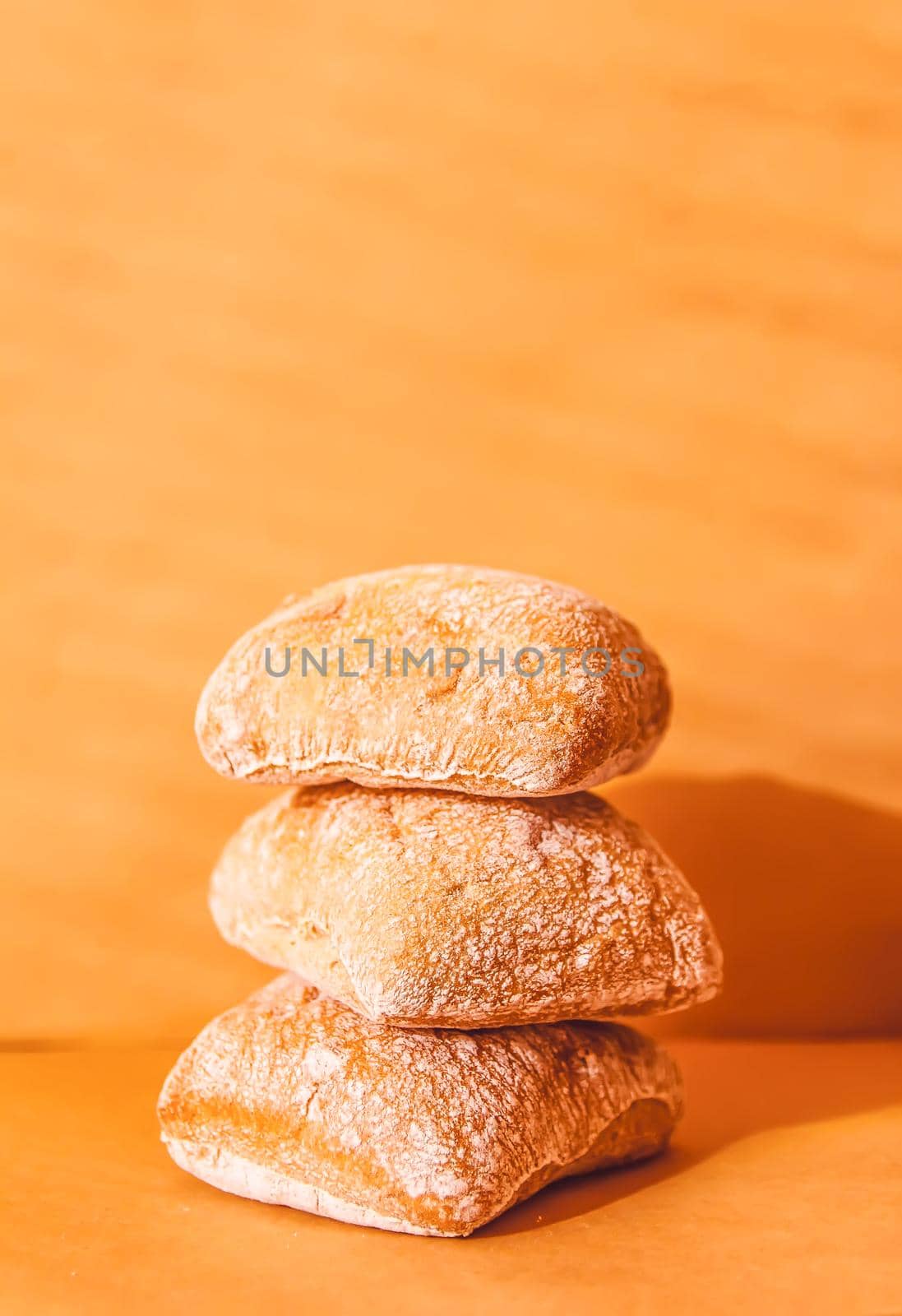 Stack of small ciabatta bread loaves in warm soft light