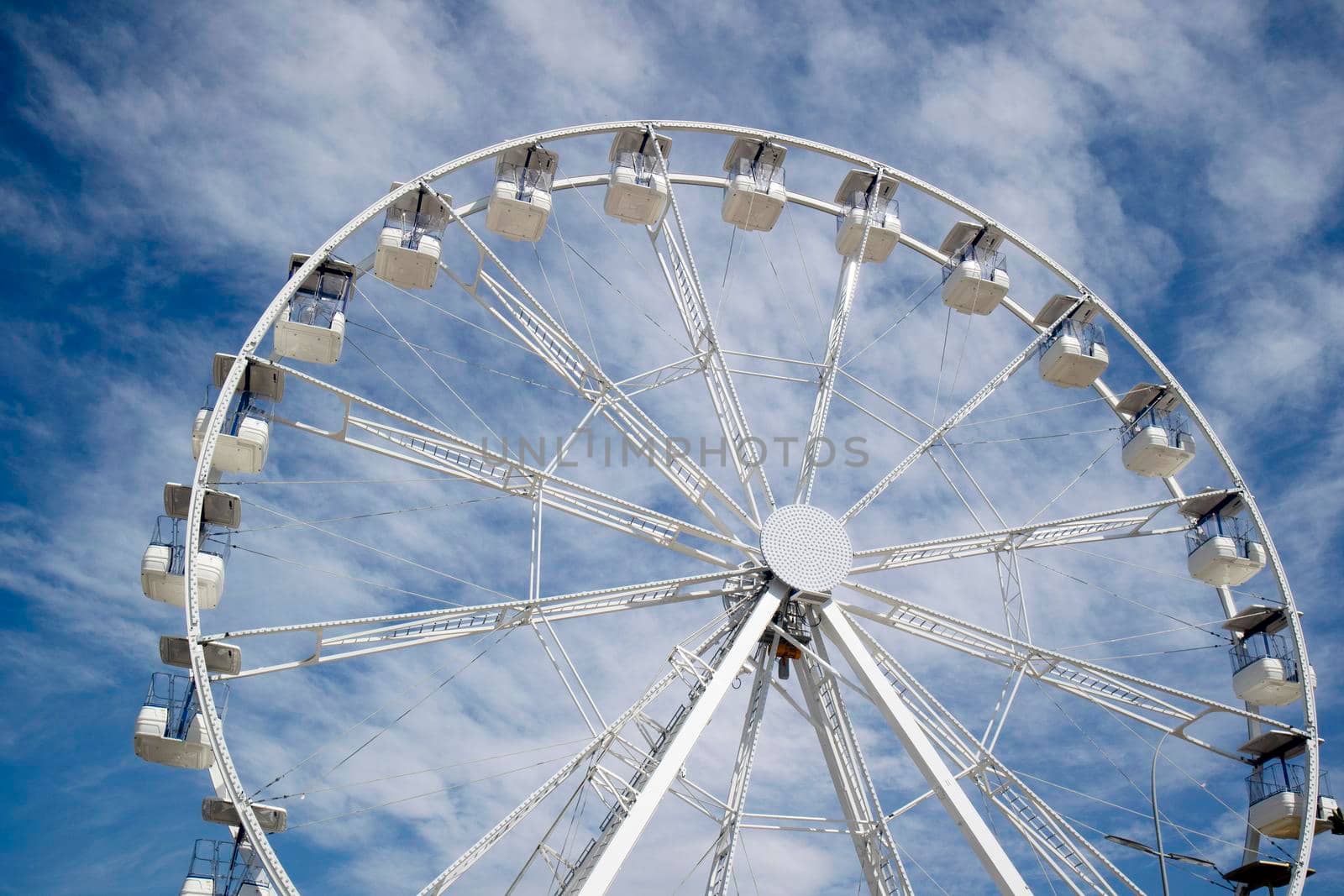 Ferris wheel of white color in blue sky  by fotografiche.eu