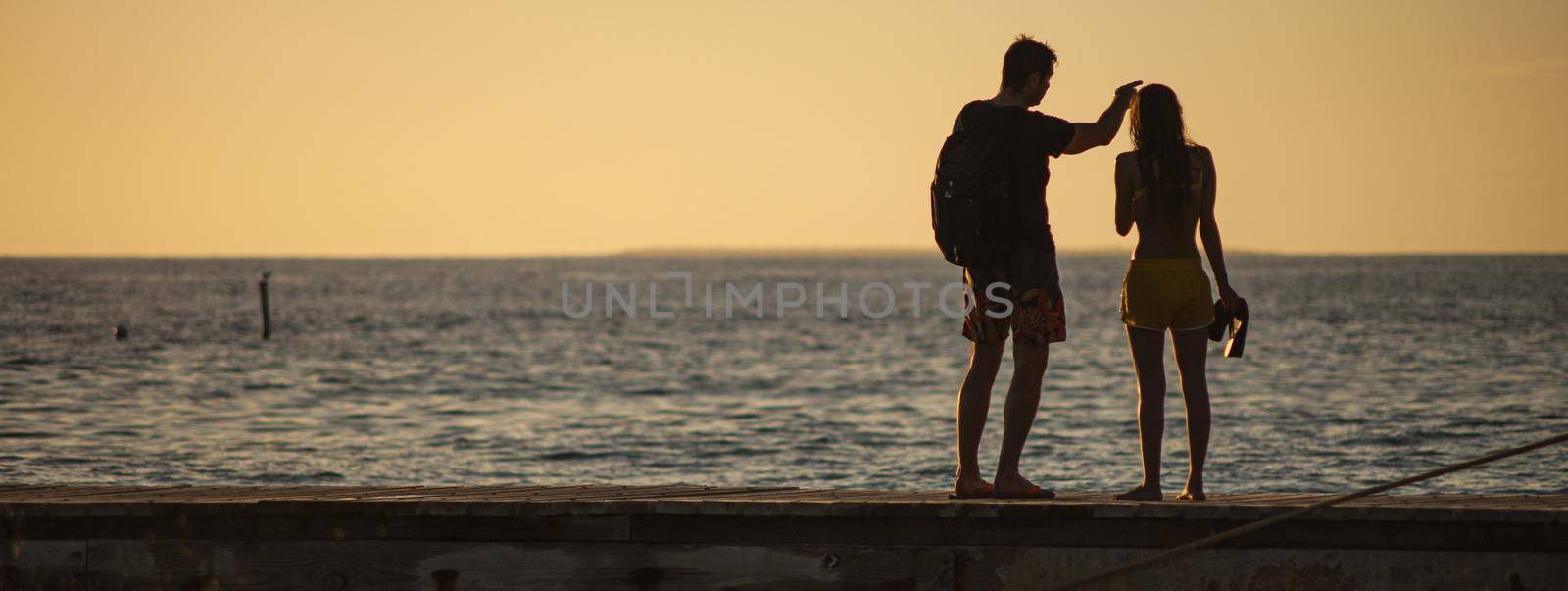 Couple on sunset pier vacation by pippocarlot